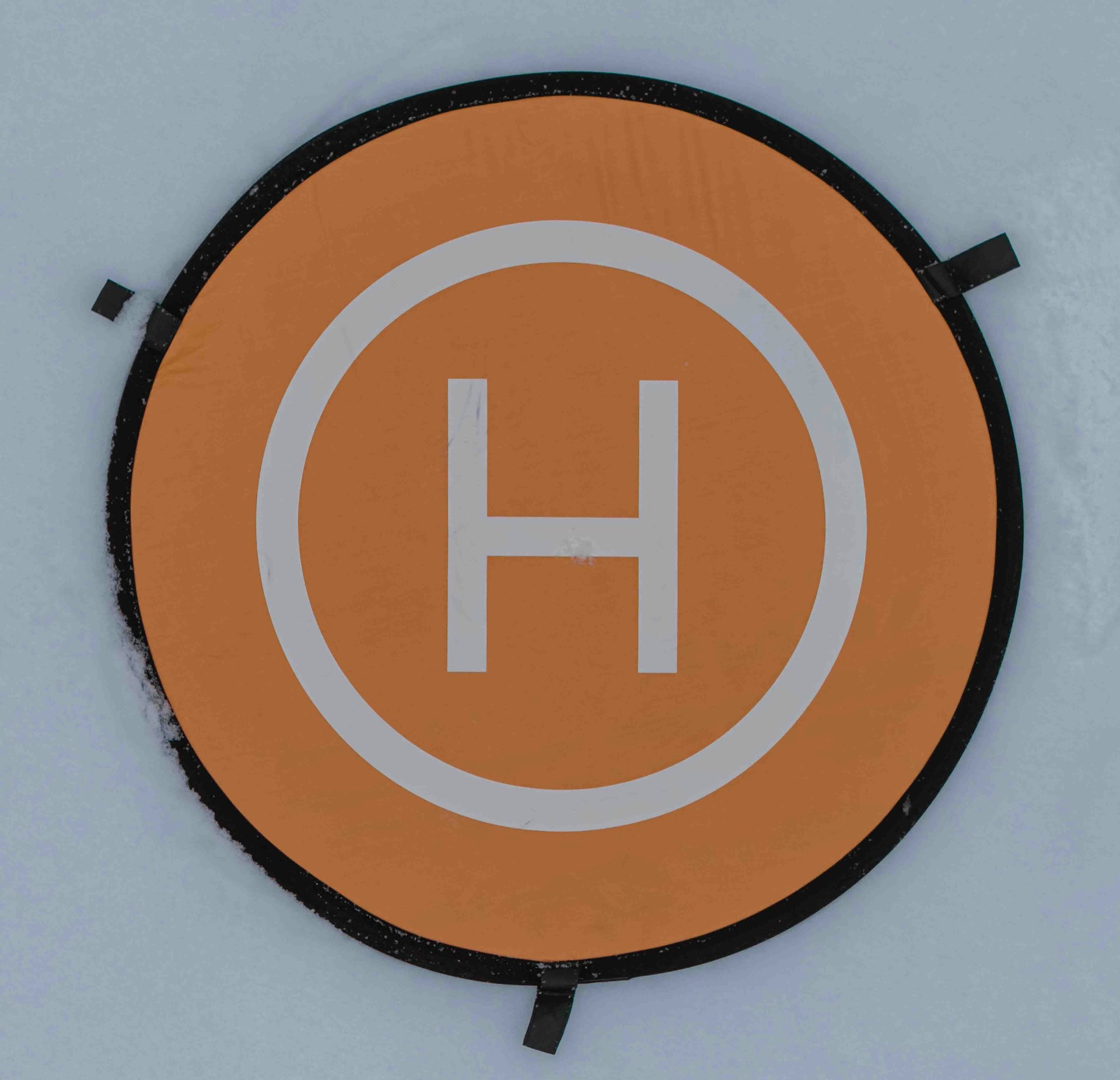 Orange helipad with a white h symbol.